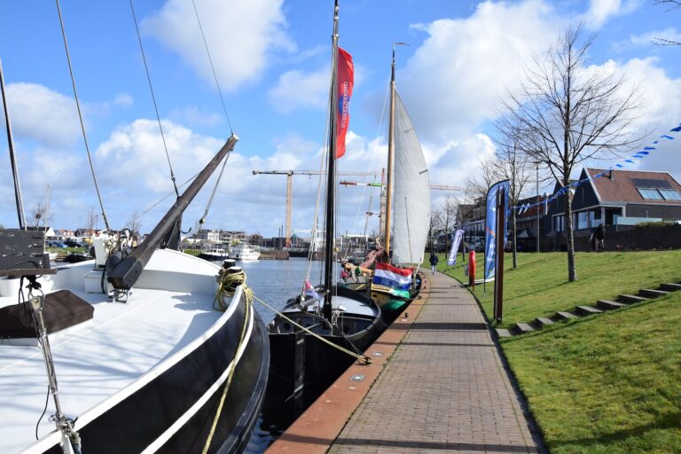 Schepen met vlaggen en zeilen aan de kade