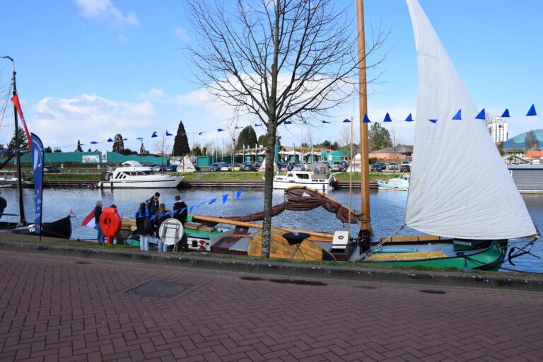 Zeilboot met wit zeil aan de kade