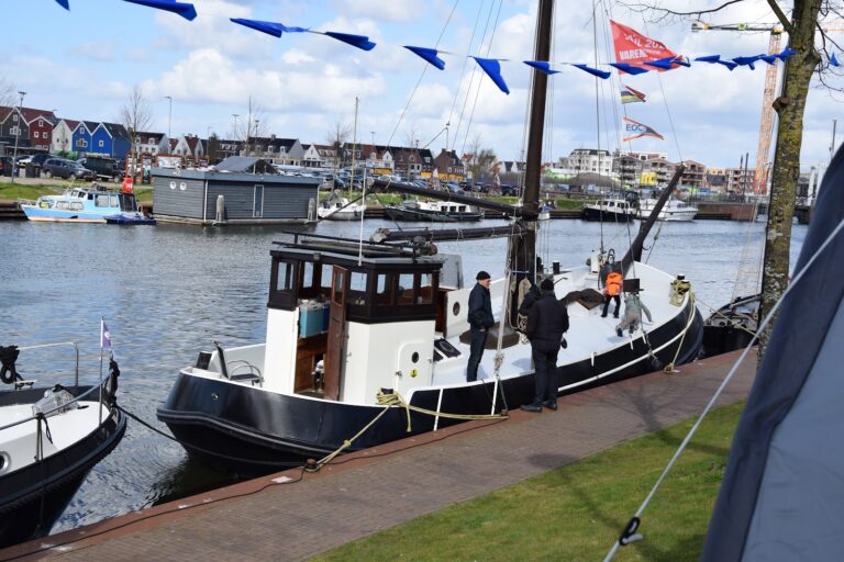 Historische sleepboot met vlaggetjes aan de kade